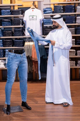 رجل إماراتي يتسوق لشراء الجينز في متجر ملابس