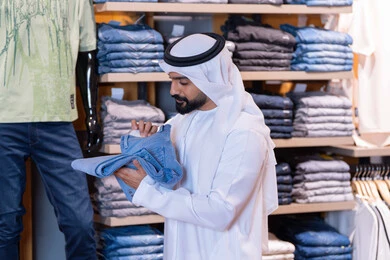 رجل عربي يتسوق لشراء الملابس في متجر تجزئة