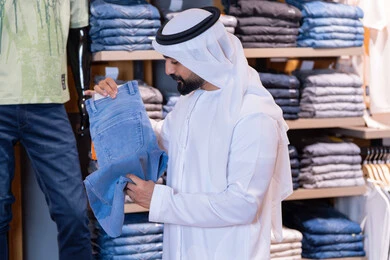 رجل إماراتي يتسوق لشراء الملابس في المتجر