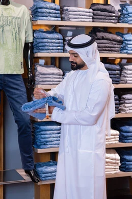رجل إماراتي يتسوق لشراء ملابس الجينز في متجر عصري