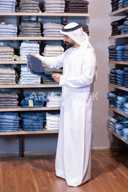 رجل عربي بالثوب التقليدي يتسوق في متجر ملابس