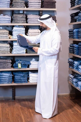 رجل عربي بالثوب التقليدي يتسوق في متجر ملابس