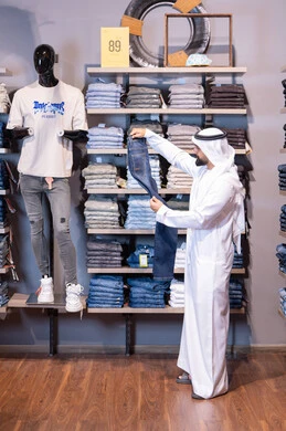 رجل إماراتي يتسوق لشراء ملابس في متجر عصري