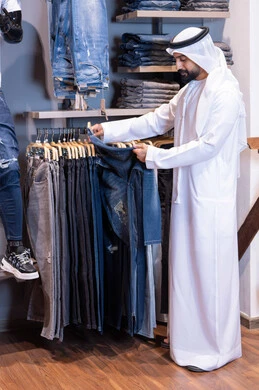 رجل إماراتي يتسوق لشراء الملابس في متجر حديث