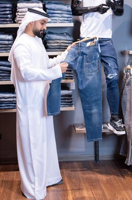 رجل إماراتي يتسوق لشراء ملابس جينز في متجر