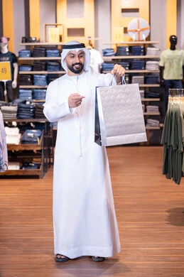 رجل عربي مع حقيبة تسوق في متجر ملابس