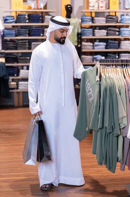 رجل إماراتي يتسوق لشراء الملابس في متجر تجزئة