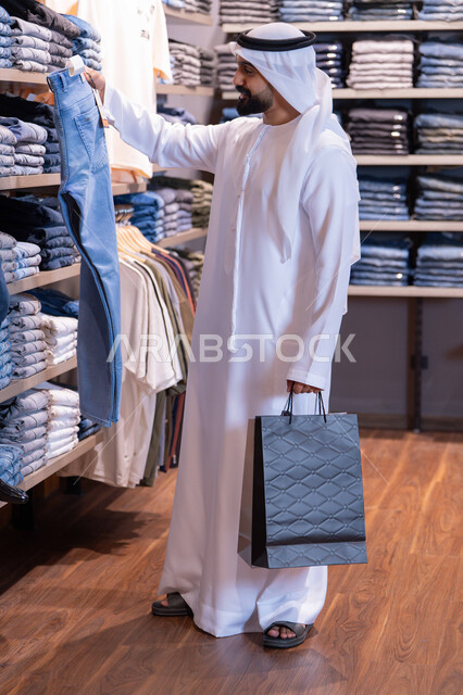 رجل إماراتي يتسوق لشراء الملابس في المتجر