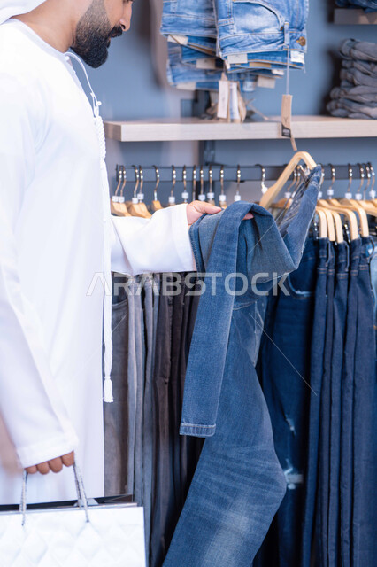رجل عربي يتسوق لشراء بنطال جينز في متجر ملابس