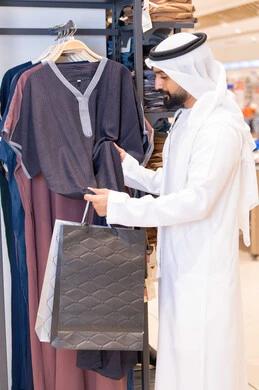 رجل إماراتي يتسوق لشراء الملابس في متجر حديث