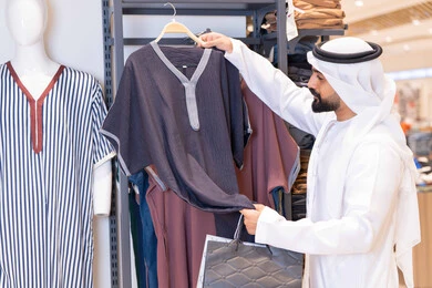 رجل عربي يتسوق لشراء الملابس التقليدية في المتجر