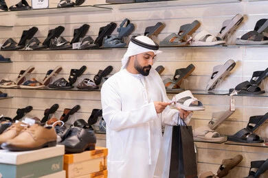 رجل إماراتي يتسوق لشراء أحذية تقليدية في المتجر