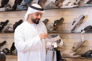 رجل إماراتي يتسوق لشراء أحذية تقليدية في المتجر