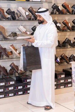 رجل إماراتي يتسوق لشراء الأحذية في متجر تجزئة
