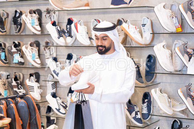 رجل إماراتي يتسوق لشراء أحذية رياضية في متجر حديث