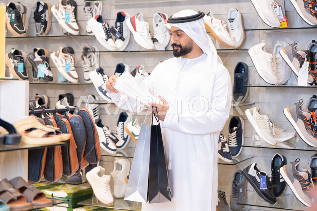 رجل إماراتي يتسوق لشراء الأحذية الرياضية في المتجر