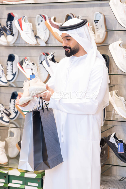 رجل إماراتي يتسوق لشراء أحذية في متجر عصري