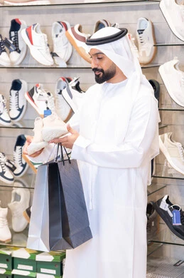 رجل إماراتي يتسوق لشراء أحذية في متجر عصري