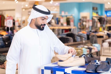 رجل إماراتي يتسوق لشراء أحذية في متجر ملابس