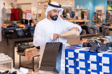 رجل إماراتي يتسوق لشراء الأحذية في متجر