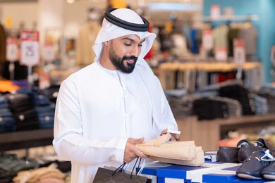 رجل إماراتي يتسوق لشراء الأحذية في متجر ملابس