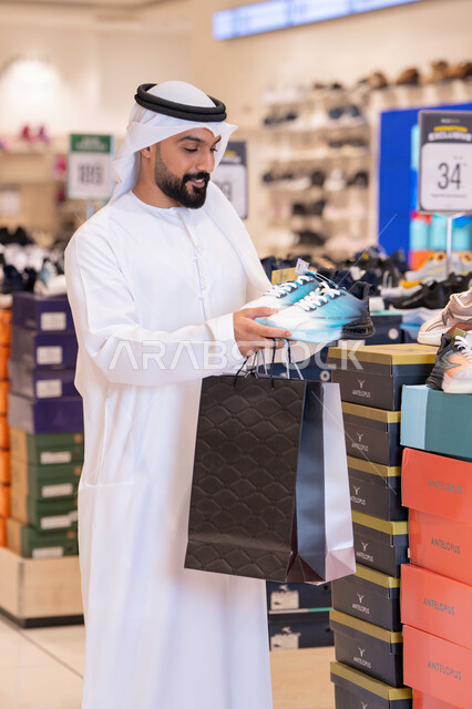 رجل إماراتي يتسوق لشراء الأحذية الرياضية في المول