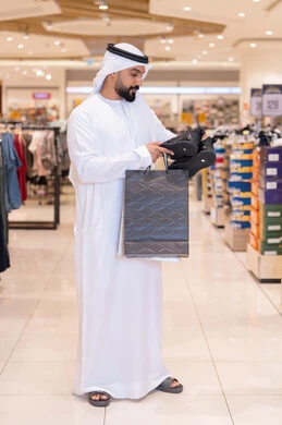 رجل إماراتي يحمل حقائب تسوق في مركز تجاري حديث