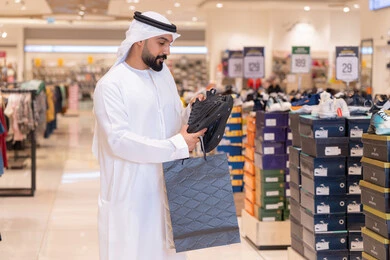رجل إماراتي يتسوق لشراء أحذية رياضية في المول