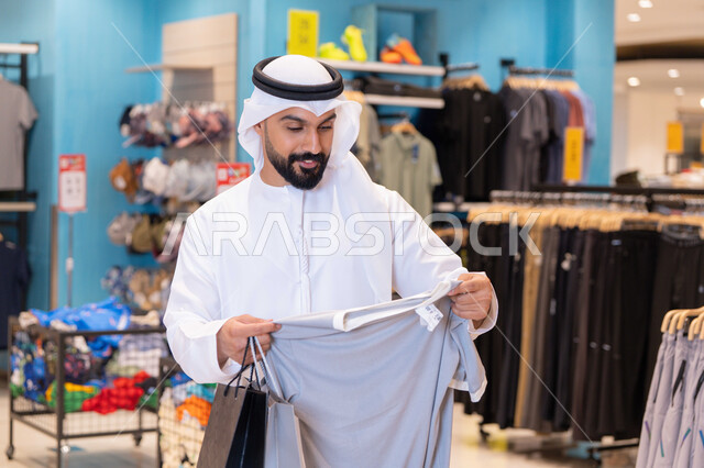 رجل إماراتي يتسوق الملابس في متجر عصري