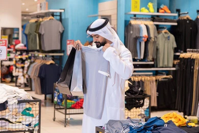 رجل إماراتي يتسوق في متجر ملابس حديث