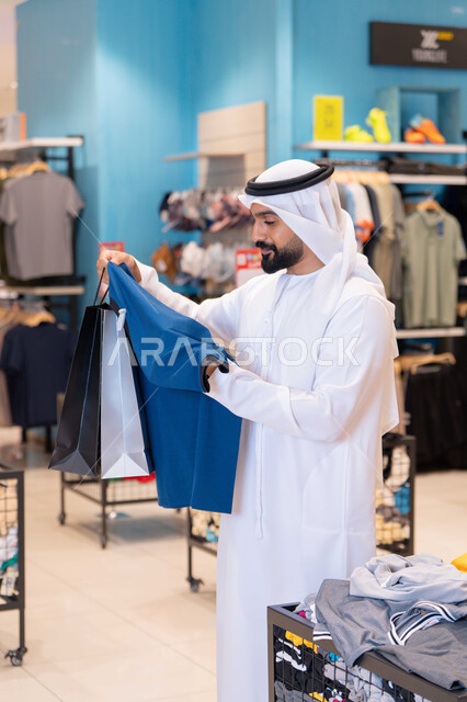رجل إماراتي يتسوق لشراء الملابس في متجر حديث