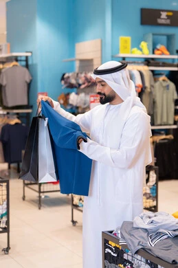 رجل إماراتي يتسوق لشراء الملابس في متجر حديث