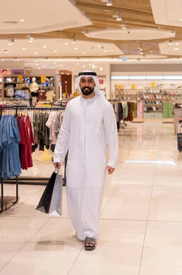 رجل إماراتي يحمل حقائب تسوق في مول حديث