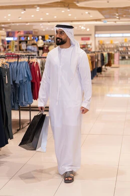 رجل إماراتي بالكندورة يتسوق في مركز تجاري