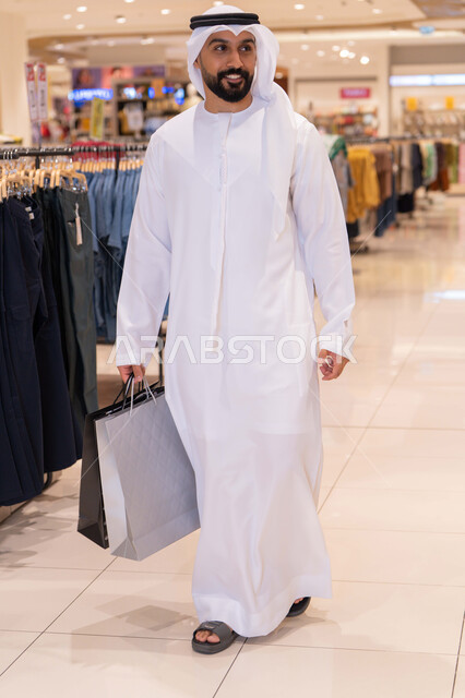 Emirati Man Walking in Mall with Shopping Bags