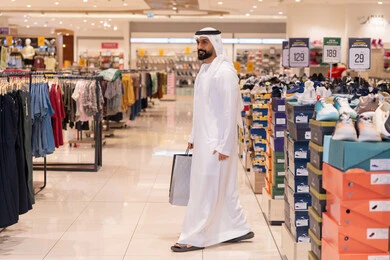 رجل إماراتي يتسوق في متجر ملابس مع حقائب