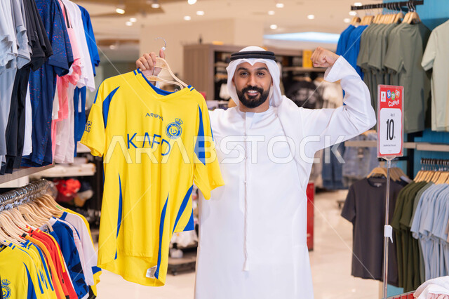 رجل سعودي يحمل قميص نادي النصر في متجر ملابس
