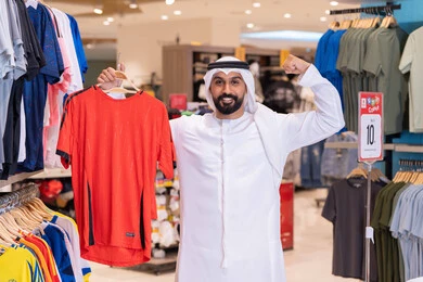 رجل إماراتي يتسوق لشراء قميص رياضي في المتجر