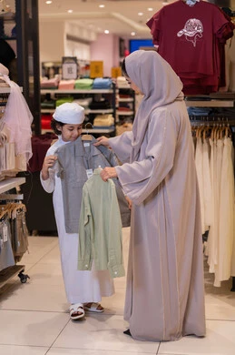 أم إماراتية وابنها يتسوقون الملابس في مركز تجاري