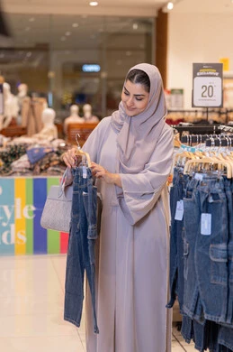 امرأة عربية تتسوق لملابس الأطفال في متجر تجاري