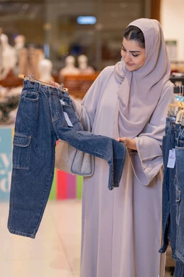 امرأة سعودية تتسوق لملابس الأطفال في المتجر امرأة سعودية تتسوق لملابس الأطفال في المتجر