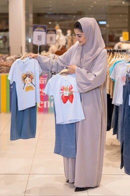 امرأة سعودية تتسوق ملابس أطفال في المول