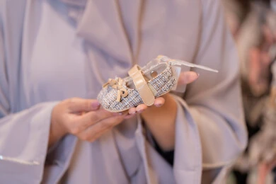 Arab Woman Holding Baby Shoe in Store