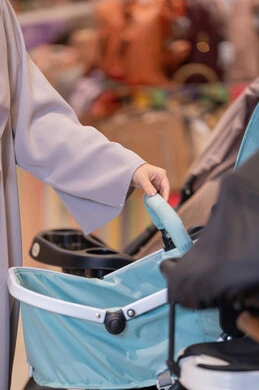 امرأة عربية تتسوق لشراء عربة أطفال في متجر