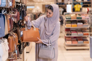 امرأة سعودية تتسوق لشراء حقائب يد في متجر