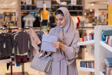 امرأة عربية تتسوق الإكسسوارات في متجر ملابس
