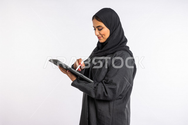 بورتريه لمرأة عربية خليجية سعودية ، تقوم بإستخدام جهاز التابلت لإنجاز المهام ، العمل عن بعد ، التسليه والترفيه ، جلسة عمل ، مهن و وظائف ، مفهوم التكنولوجيا وإستخدام أجهزة تقنية حديثة ، التسويق الإلكتروني ، تصفح الإنترنت، إستخدام وسائل التواصل الإجتماعي