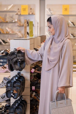 امرأة عربية تتسوق لشراء الأحذية في متجر تجزئة