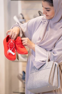 امرأة سعودية تتسوق لشراء أحذية رياضية حمراء