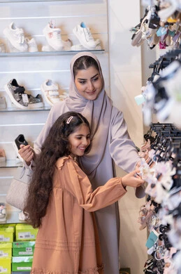 أم سعودية وابنتها تتسوقان الأحذية في متجر تجزئة